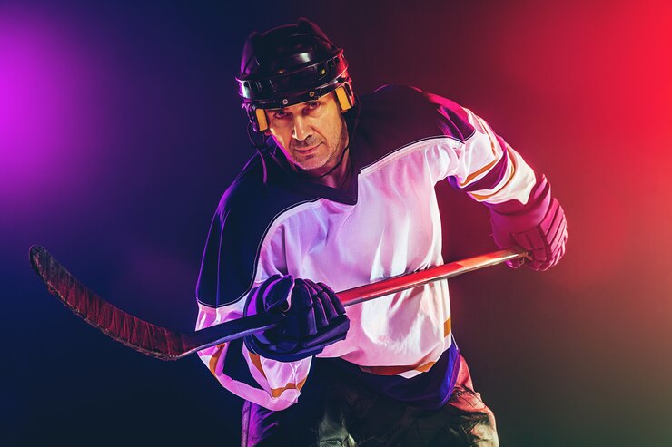 male-hockey-player-with-stick-ice-court-dark-neon-colored-wall_155003-31959